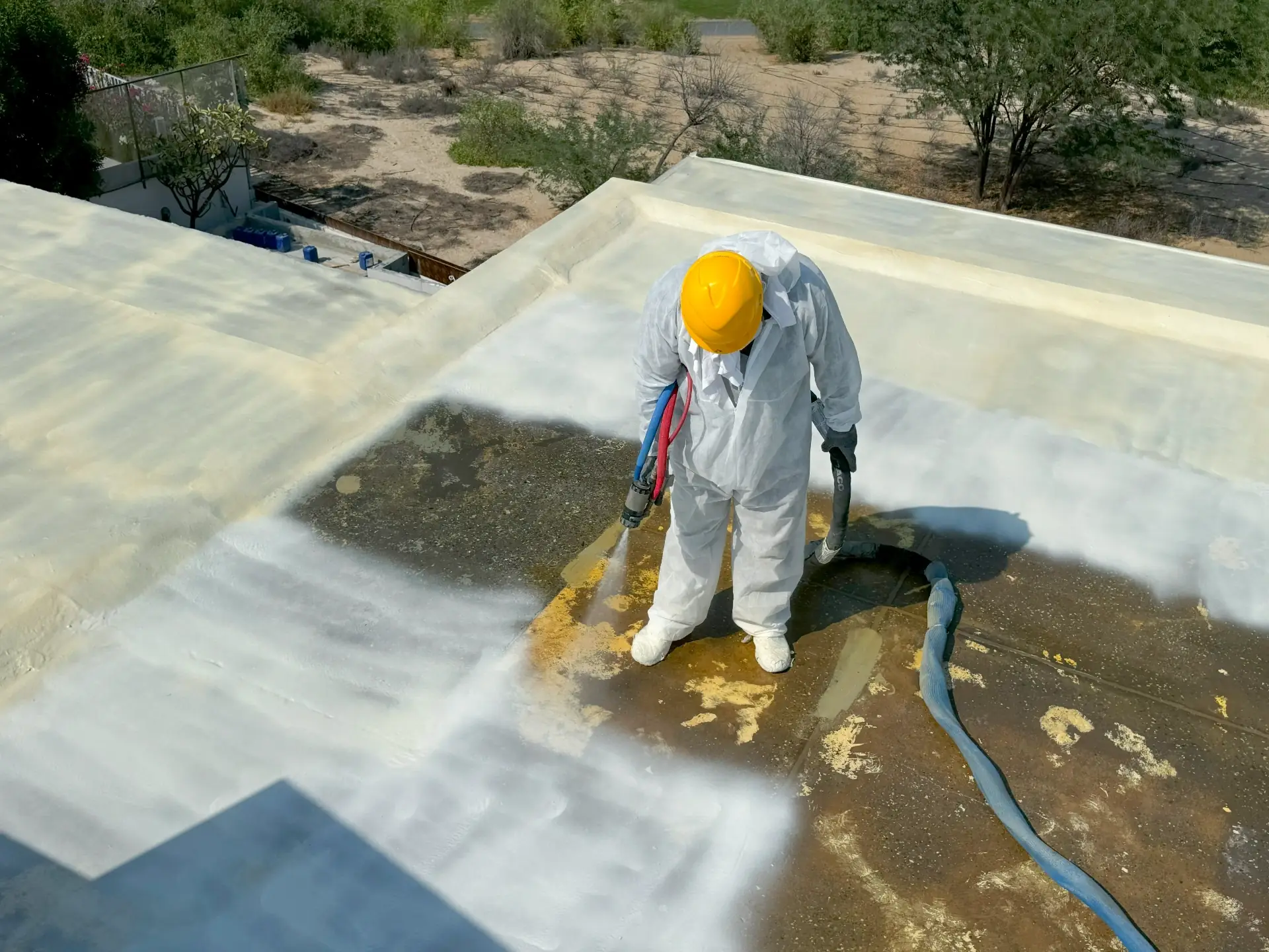 Halo Shield engineer removing failed bitumen and spraying a seamless polyurea membrane on a Dubai villa flat roof